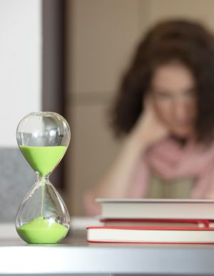 Sanduhr und Bücher, im Hintergrund eine Person